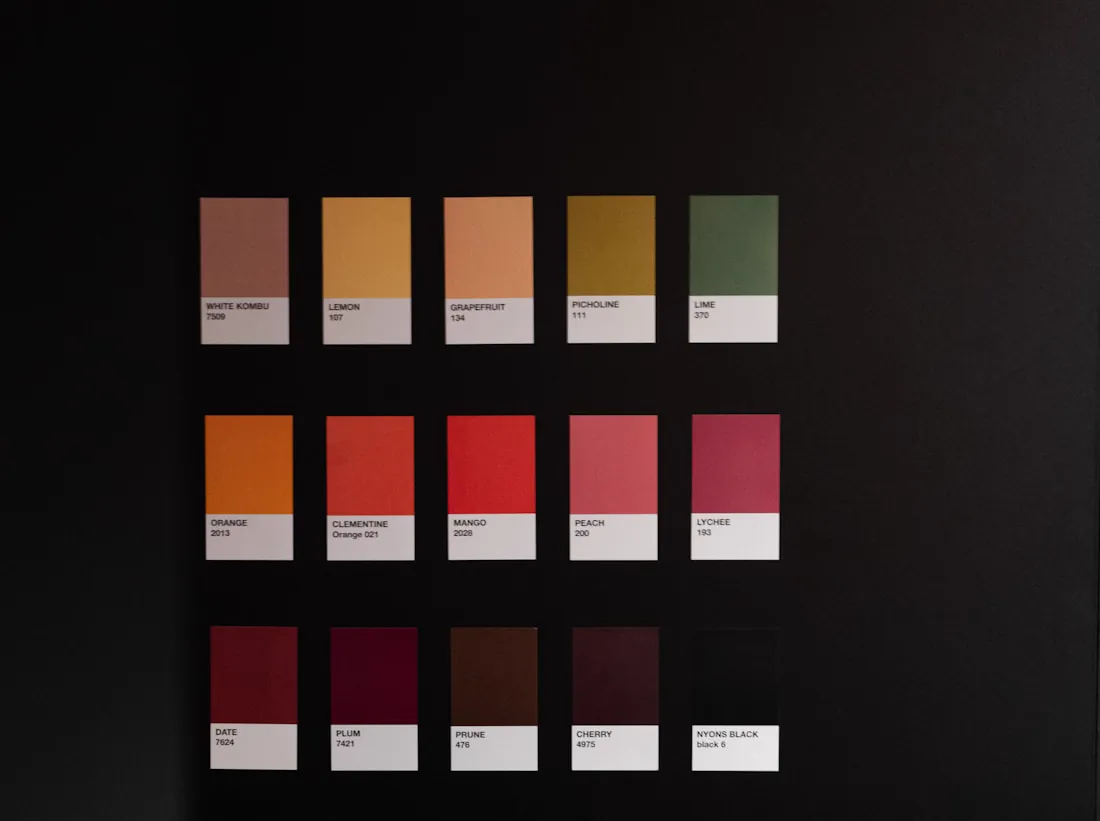 Printed colour swatches in warm oranges and reds on a black surface