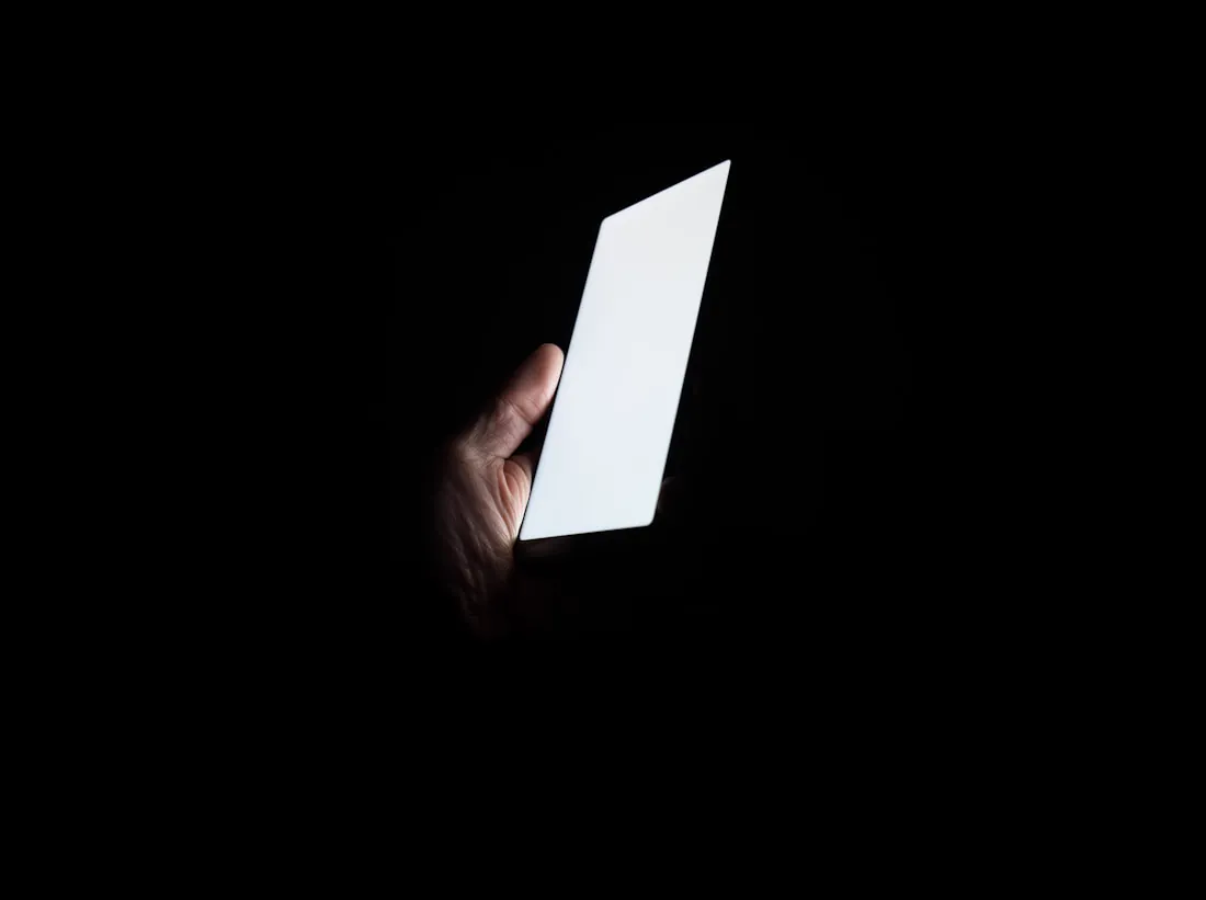 A customer searching on a brightly lit phone screen in the dark